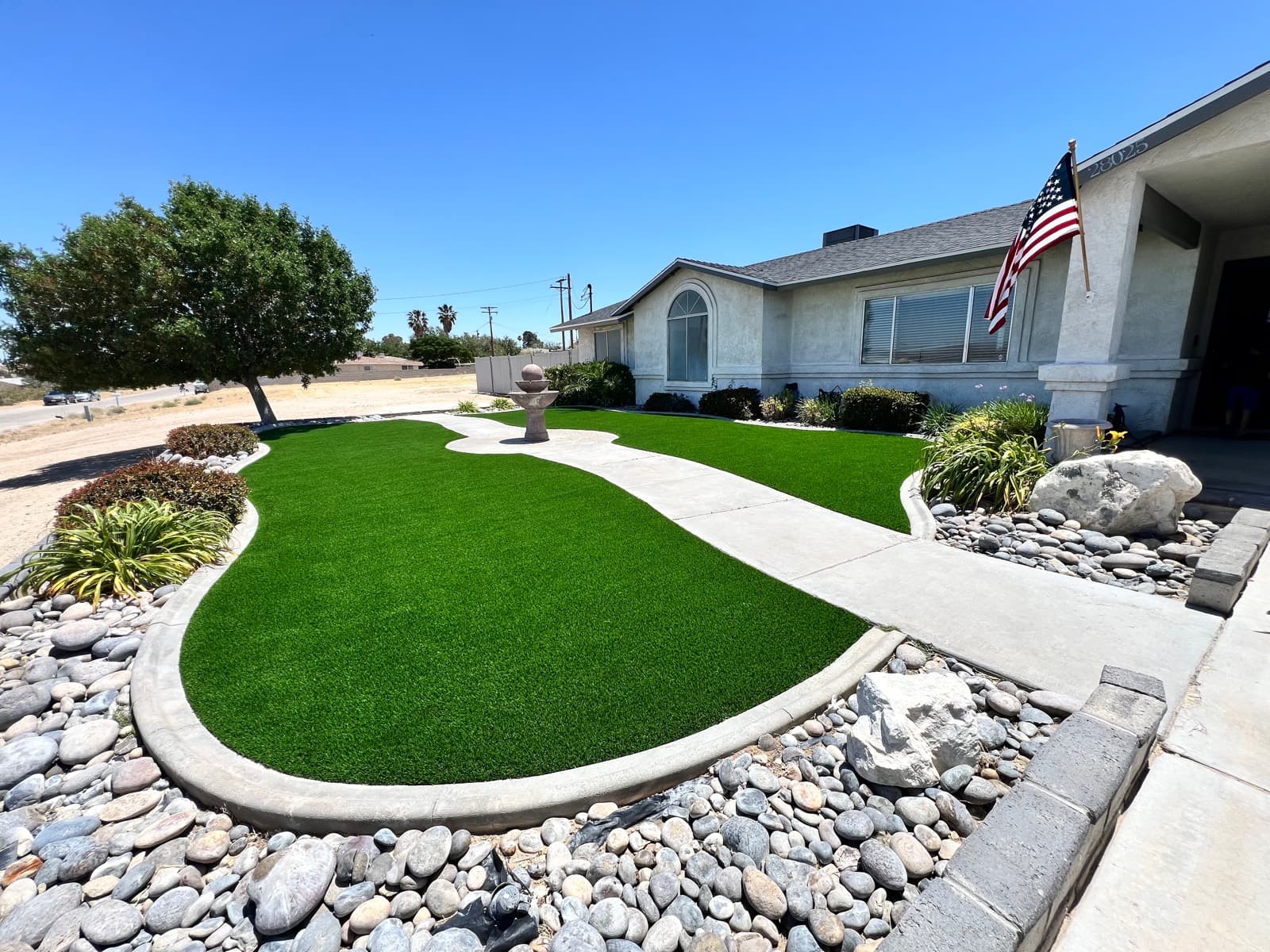 Front yard with two curved turf panels, river rock, and a fountain