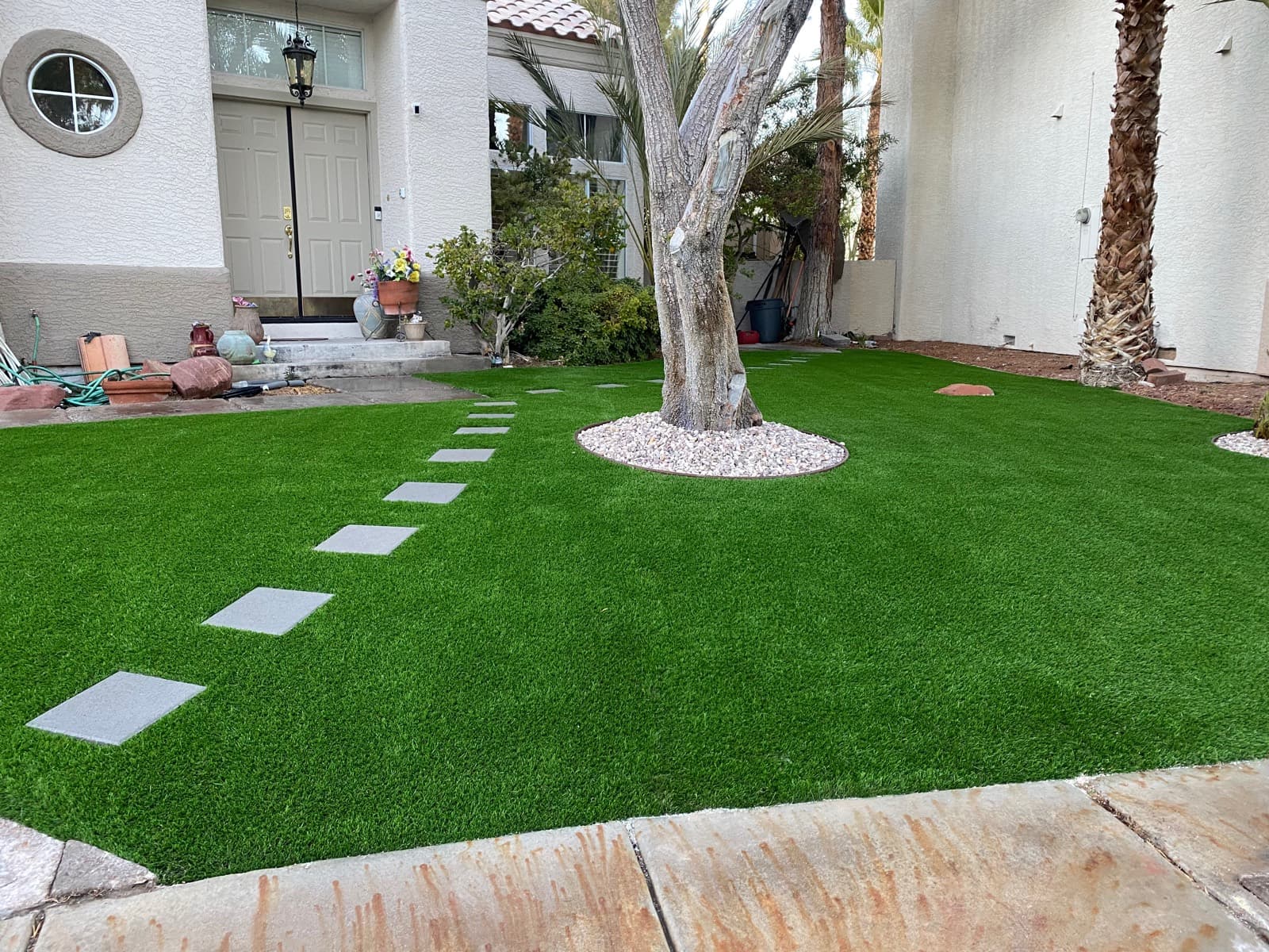 Front-yard turf with square stepping stones and a gravel tree ring