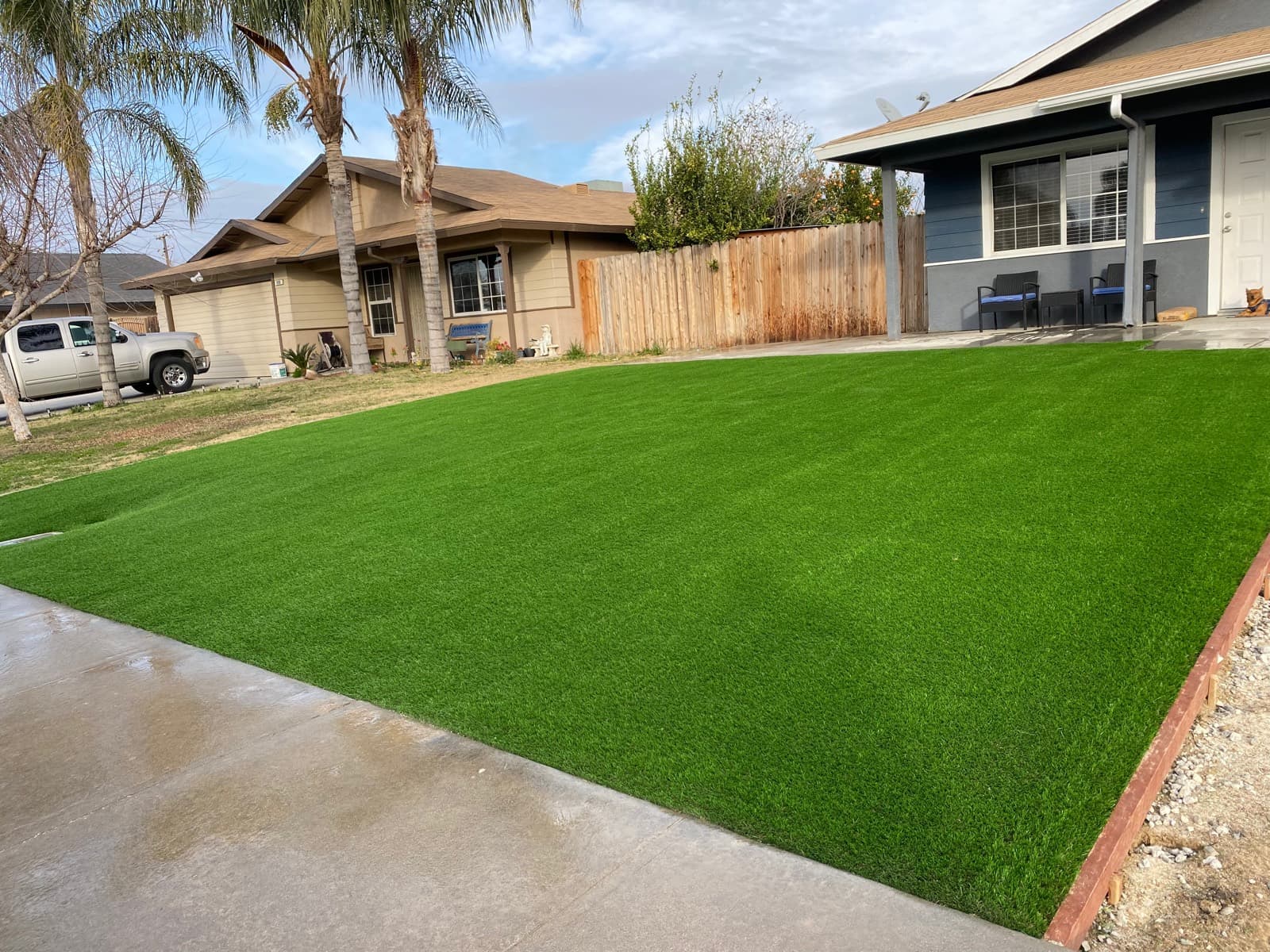 Rectangular front-yard turf lawn in front of a blue house