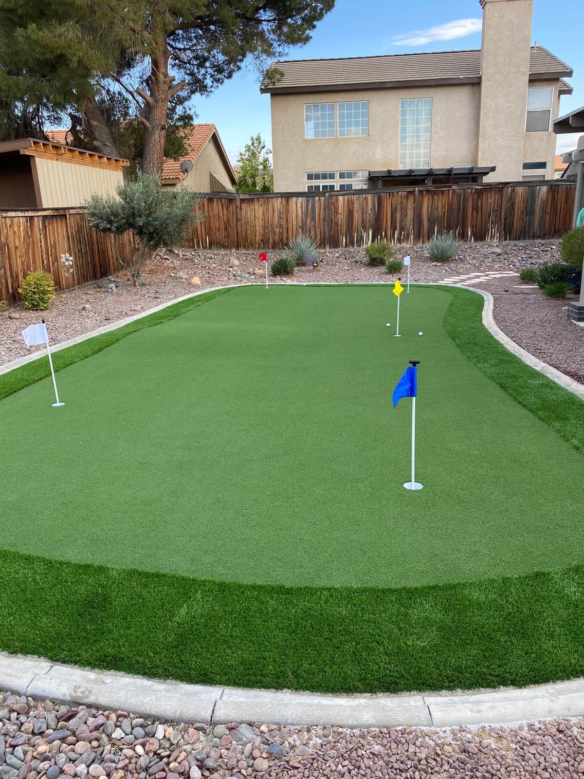 Backyard putting green with fringe turf, flags, and a scalloped curb