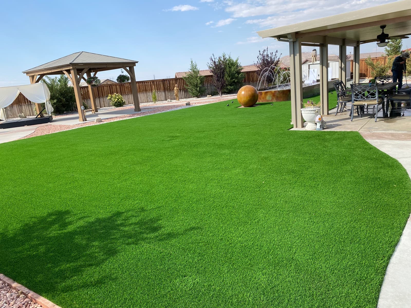 Large backyard turf lawn with a gazebo and covered patio