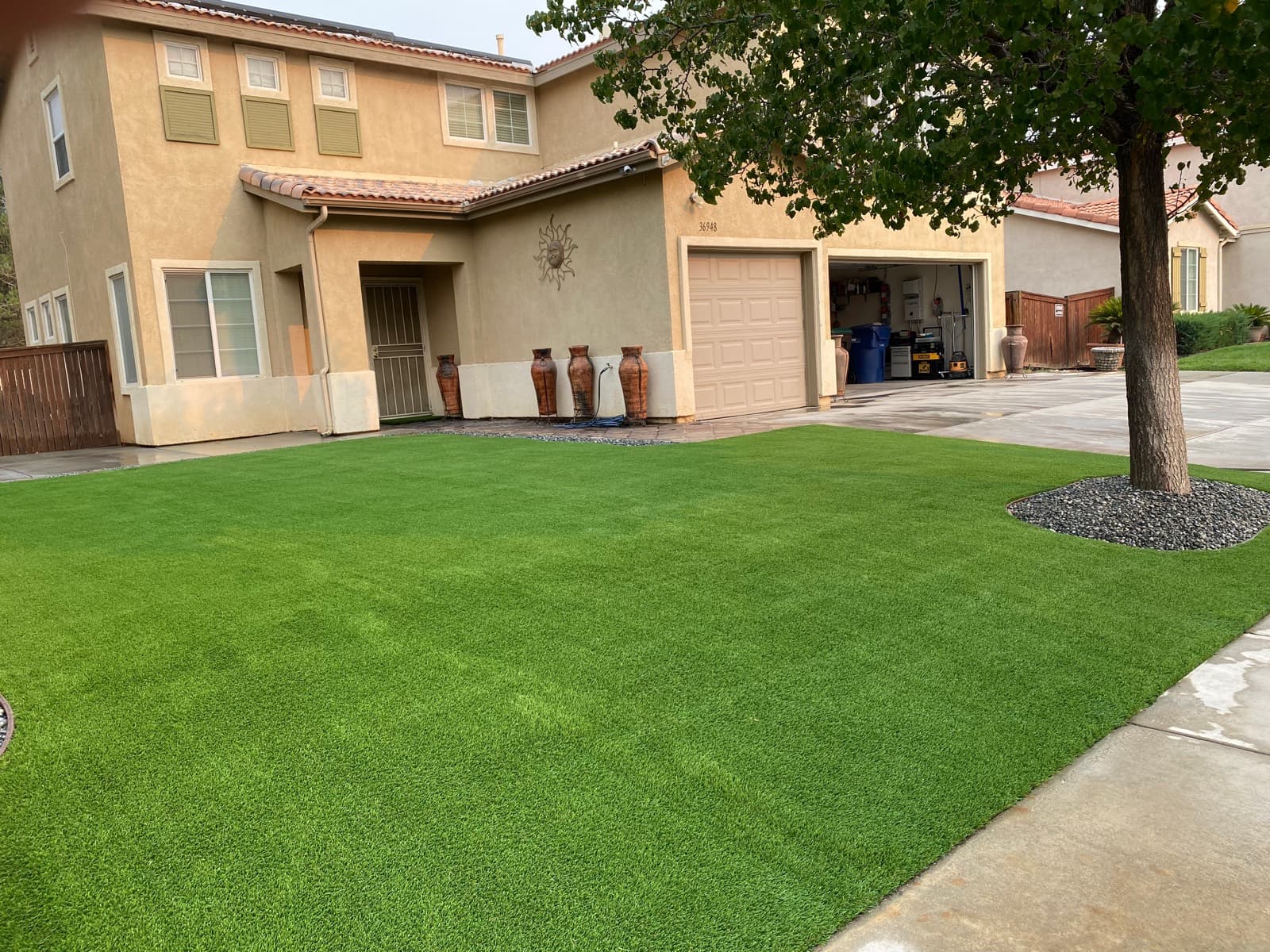 Front-yard turf lawn with a gravel tree ring and house foundation border