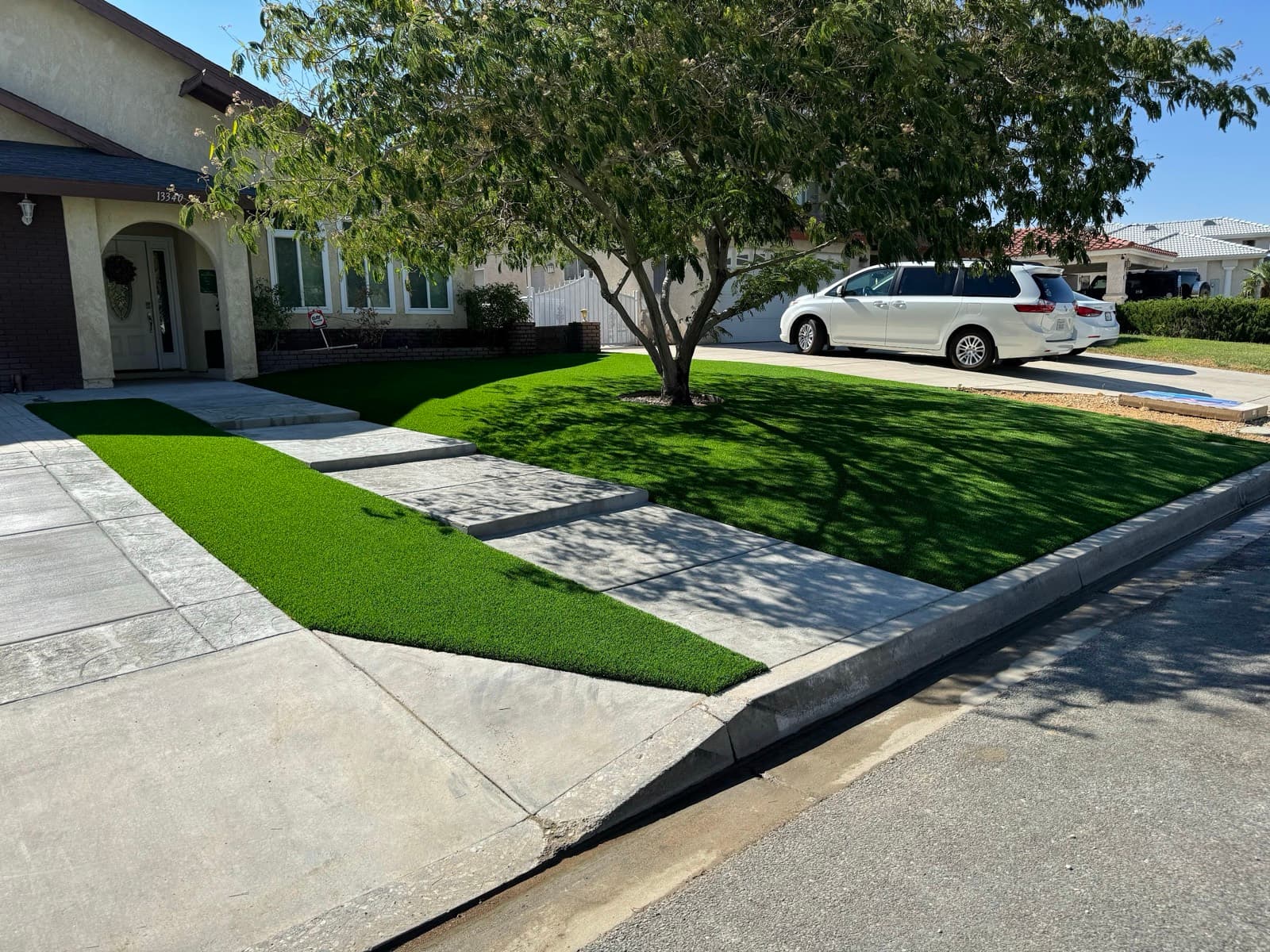 Turf ribbons between large concrete pavers leading to a house