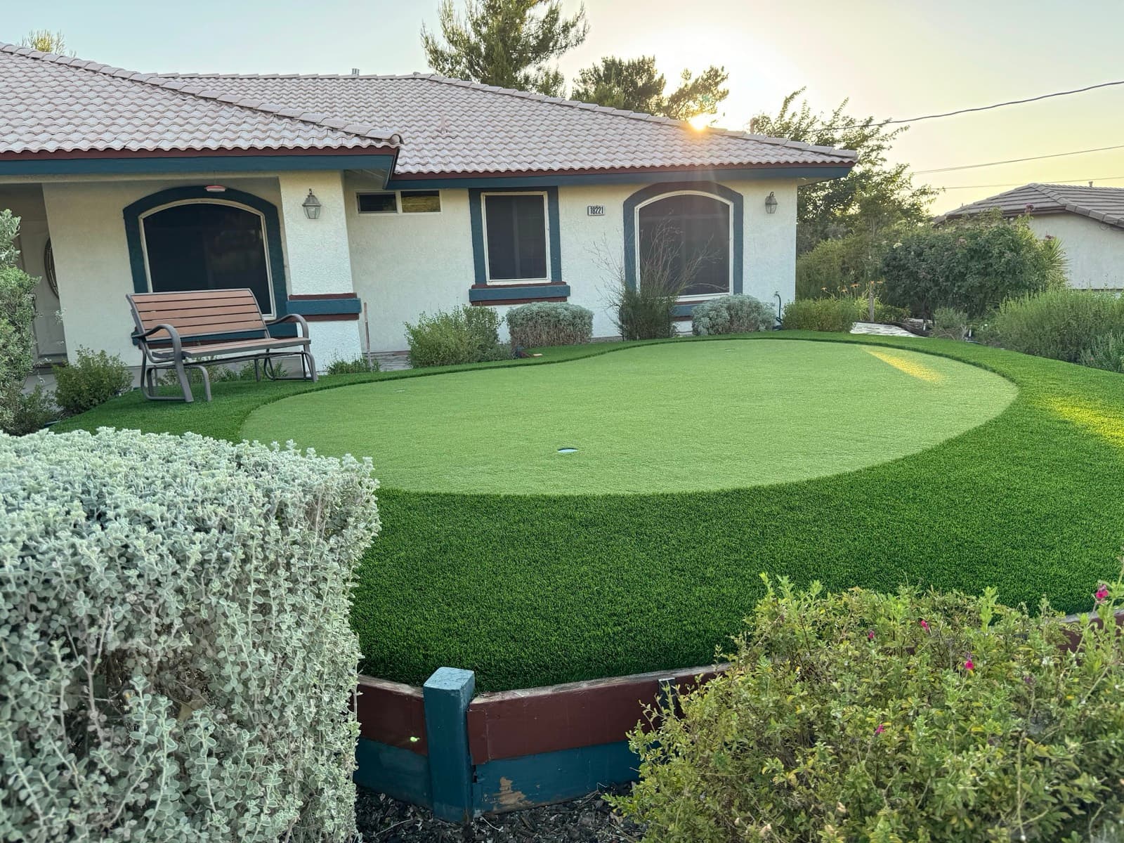 Sunset backyard putting green with a fringe and a garden bench