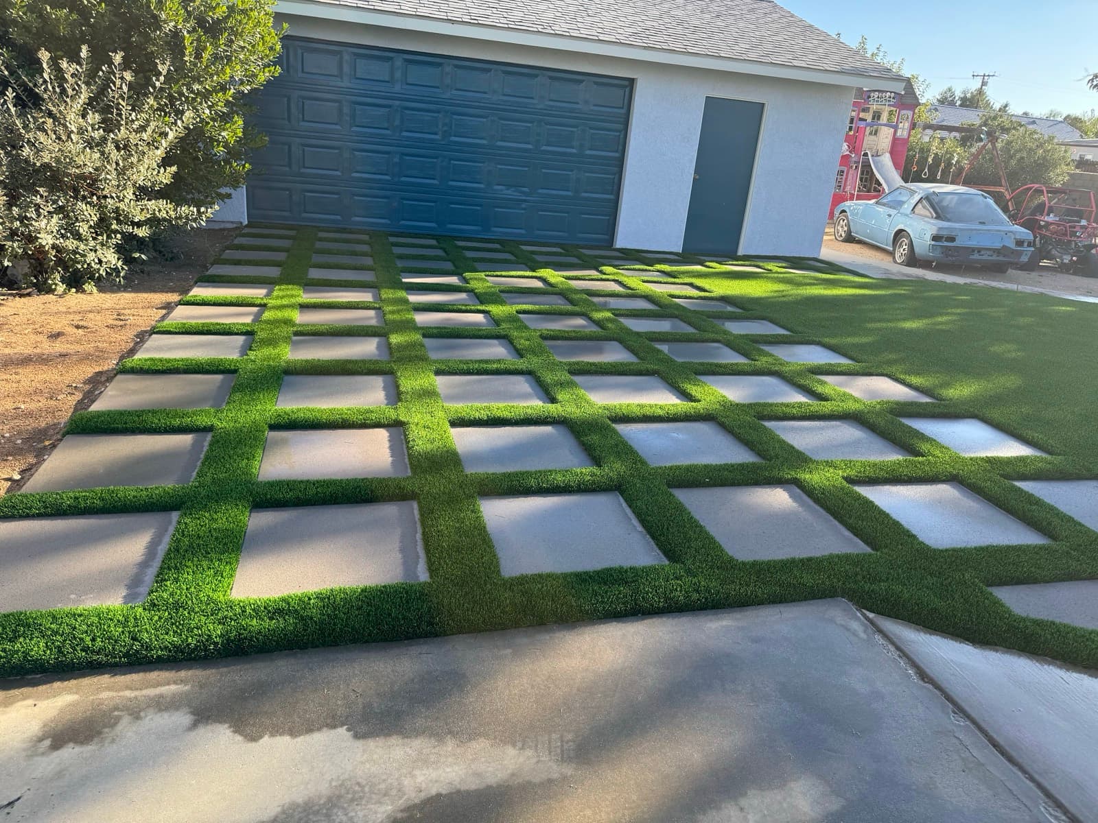 Grid of square concrete pavers with turf in the joints