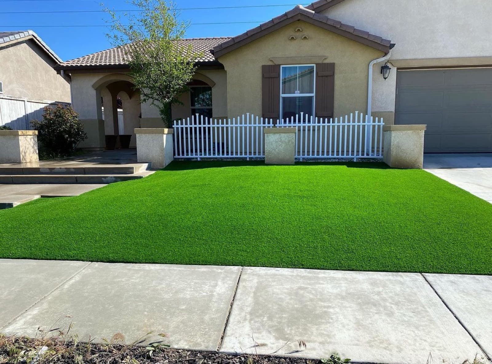 Rectangular front-yard turf lawn against a sidewalk and stucco house
